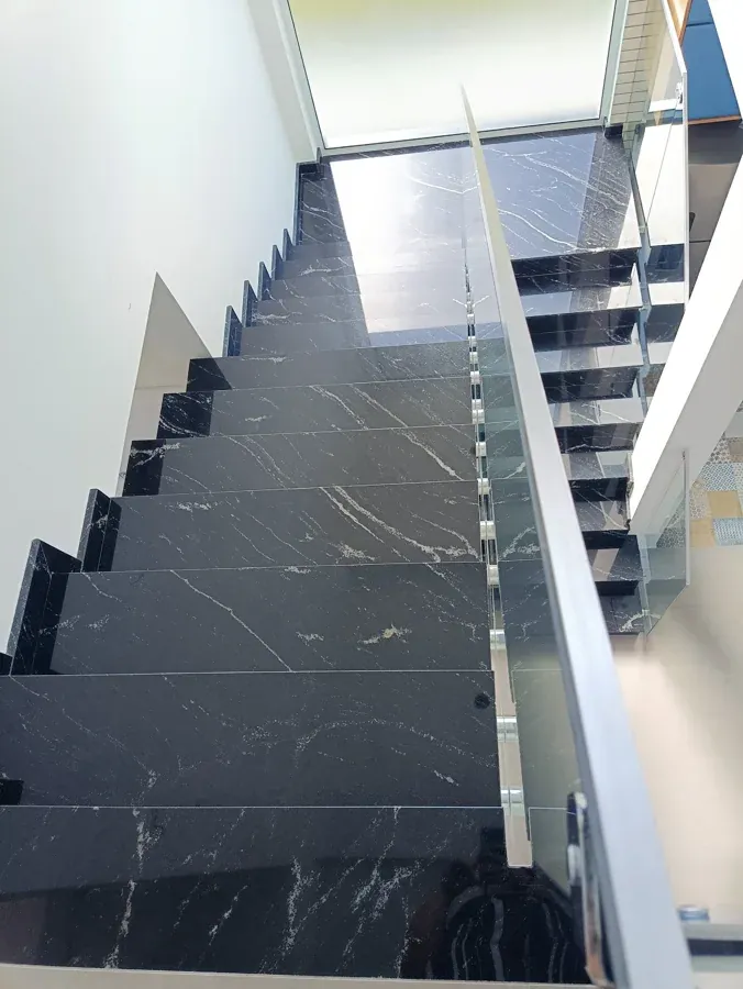 Escada revestida em pedra escura com veios claros